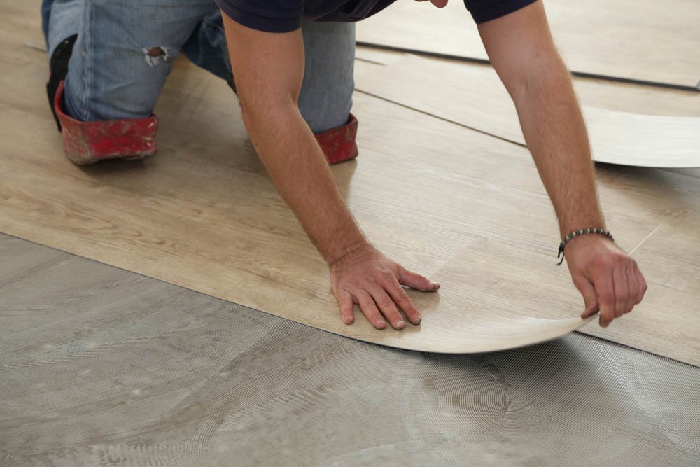 work on laying flooring. worker installing new vinyl tile floor.